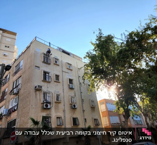 אדם עובד בגובה על בניין עם ציוד בטיחות